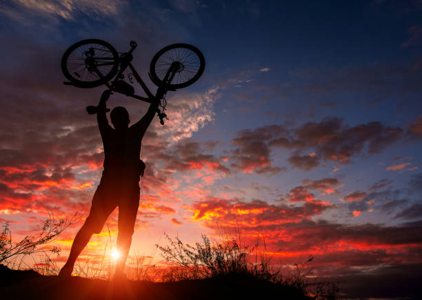 cyclist with a bicycle in Uganda, admiring the fiery sunset.