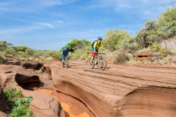 Two well experienced mountain bikers are riding at the very edge of a litte canyon nearby Lake Chala in T during their Tanzania cycling tours.